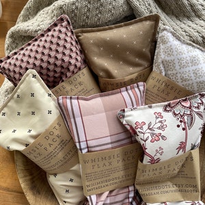 May include: Five different patterned flax seed heat packs with brown paper labels that say "Whimsy Dots Flax Pack" and instructions for use. The labels also include the Etsy shop name and Instagram handle.