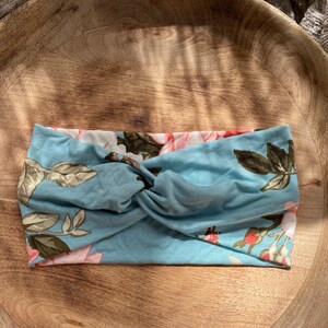 May include: A blue headband with a floral pattern. The headband is twisted and has a knot in the center.
