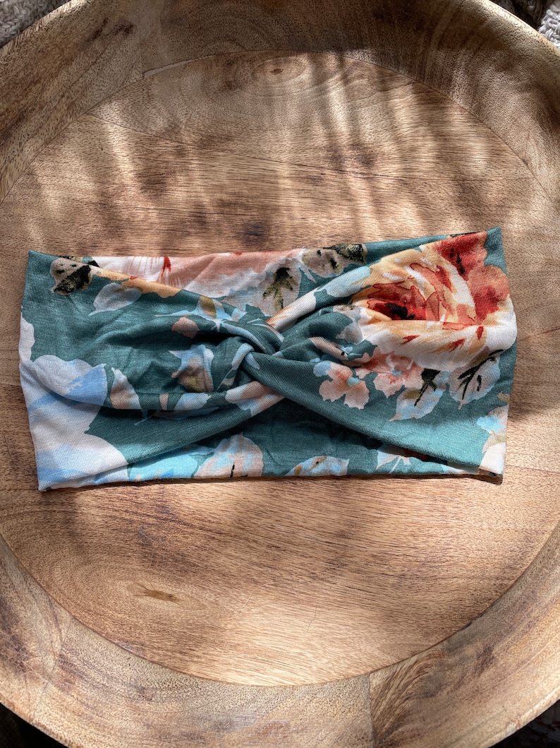 May include: A green and white floral patterned headband with a twisted knot in the center.