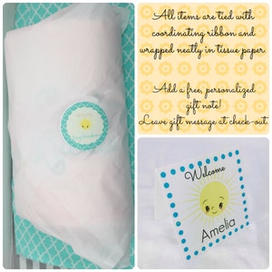 May include: A gift wrapped in white tissue paper, tied with a ribbon, and sealed with a round sticker that says "enjoy Tiny Sunshine". A welcome card with a sun graphic and the name "Amelia" is also included.