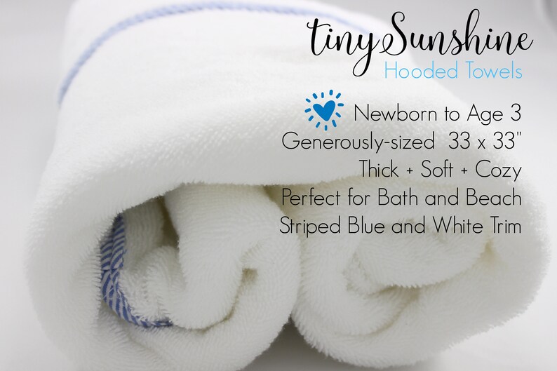 May include: A white hooded towel with blue and white striped trim. The towel is rolled up and is labeled "tiny Sunshine Hooded Towels". The text also says "Newborn to Age 3", "Generously-sized 33 x 33", "Thick + Soft + Cozy", "Perfect for Bath and Beach", and "Striped Blue and White Trim".