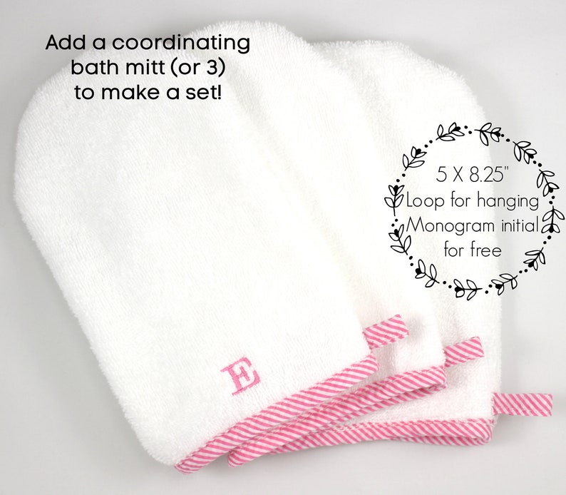 May include: White bath mitts with pink striped trim and a loop for hanging. Each mitt is embroidered with a pink initial. The mitts measure 5 x 8.25 inches.