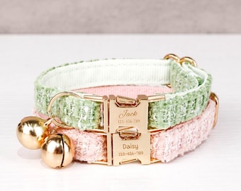 Könnte beinhalten: Zwei übereinanderliegende Katzenhalsbänder, eines hellgrün und eines rosa. Jedes Halsband hat eine goldfarbene Schnalle mit eingraviertem Namen und Telefonnummer. Goldene Glöckchen hängen am grünen Halsband.