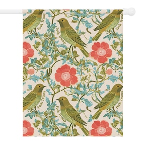 May include: A decorative garden flag featuring a repeating pattern of green birds, red flowers, and blue foliage on a cream background. The words "Fuck Trump" are printed on the flag.