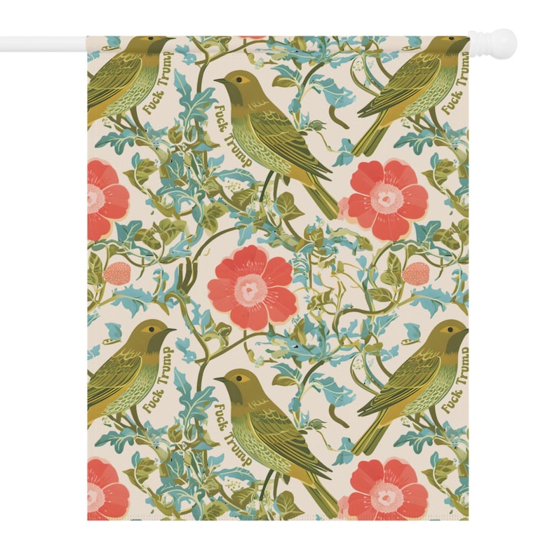 May include: A decorative garden flag featuring a repeating pattern of green birds, red flowers, and blue foliage on a cream background. The words "Fuck Trump" are printed on the flag.