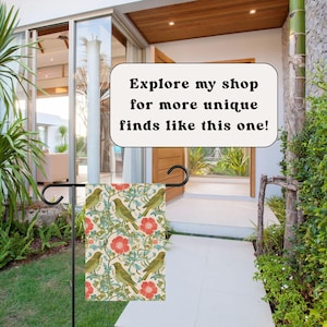 May include: A garden flag with a floral and bird pattern. The flag features a cream background with red flowers, green leaves, and green birds. The text on the image reads: Explore my shop for more unique finds like this one!