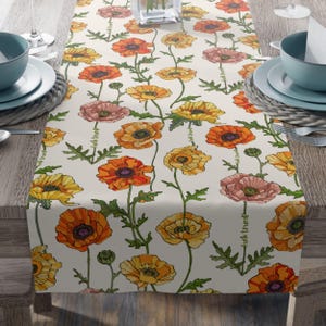 May include: A floral table runner featuring a repeating pattern of orange, yellow, and pink poppy flowers with green stems and leaves on a cream background. The text "fuck trump" is printed vertically along the edge of the runner.