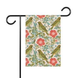 May include: A garden flag featuring a repeating pattern of green birds, red flowers, and green vines on a cream background. The words "Fuck Trump" are printed on the birds. The flag is attached to a black metal stand.