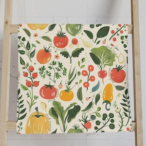 May include: A cream-colored towel with a repeating pattern of colorful vegetables and herbs. The design includes tomatoes, peppers, garlic, and leafy greens. The words "fuck trump" are written throughout the design.