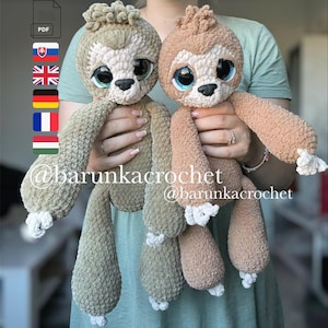 Könnte beinhalten: Zwei handgefertigte gehäkelte Faultier-Spielzeuge. Eines ist hellbraun, das andere ist hellbraun. Beide haben große, ausdrucksstarke Augen und lange Arme und Beine. Die Spielzeuge sind weich und plüschig, mit weißen Akzenten an den Füßen. Der Text "@barunkacrochet" ist sichtbar.