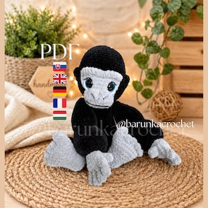 May include: A handmade crochet gorilla toy in black and gray, with blue eyes. The plush animal is sitting on a woven mat. The image includes the text "PDF" and the Instagram handle "@barunkacrochet".