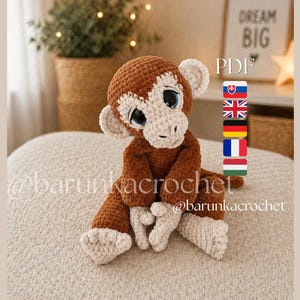 May include: A handmade crochet monkey in shades of brown and cream. The plush toy has large blue eyes and is sitting on a neutral-colored surface. The image includes the text "Dream Big" and "PDF".