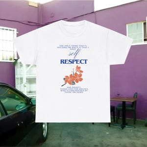 May include: White t-shirt with the text "The only thing that's holding me back is that I have self respect and dignity. Thank god for Kristen who is unburdened by those anchors." and a floral design.