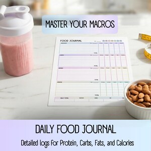 May include: A pink smoothie in a white and clear shaker bottle, a food journal, a bowl of almonds, and a measuring tape are on a white surface. The journal has the text "FOOD JOURNAL" and "MASTER YOUR MACROS". The text "DAILY FOOD JOURNAL" and "Detailed logs for Protein, Carbs, Fats, and Calories" are also visible.