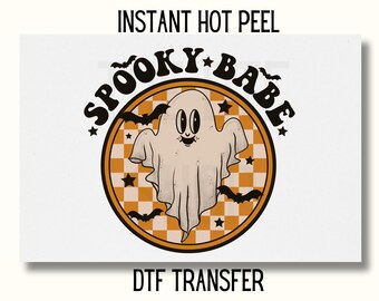 May include: A round orange and white sticker with a ghost and bats. The sticker says "Spooky Babe" in a retro font. The sticker is for use with a DTF transfer.