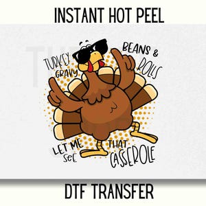 May include: A cartoon turkey wearing sunglasses and pointing with its wings. The image includes the phrases "Turkey Gravy", "Beans & Rolls", "Let Me See That Casserole", and "Instant Hot Peel DTF Transfer". The turkey is brown, with tan feathers and yellow feet.