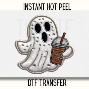 May include: A white ghost holding a brown and white iced coffee cup with a straw. The ghost is decorated with silver glitter and rhinestones. The text "INSTANT HOT PEEL DTF TRANSFER" is printed below the image.