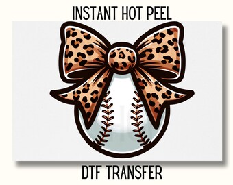May include: A white baseball with a brown and black leopard print bow tied around it. The text "INSTANT HOT PEEL" is above the baseball and the text "DTF TRANSFER" is below the baseball.