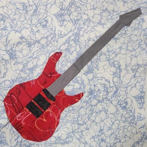 Può includere: Una chitarra elettrica rossa con un manico grigio e un battipenna nero. La chitarra è su uno sfondo bianco con un motivo a marmo blu.