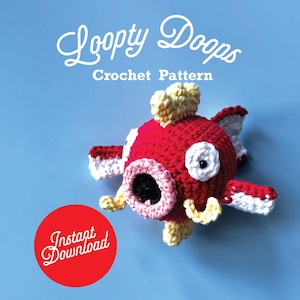 May include: A red, white, and yellow crochet fish toy with the text "Loopy Doops Crochet Pattern" and a red circle with the words "Instant Download". The fish has white and red fins, a yellow crown, and a pink and black mouth. The background is a solid light blue.
