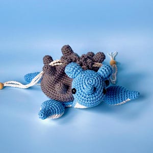 May include: A crocheted blue and brown turtle toy with a white string attached. The turtle has a brown shell with a blue head and legs.