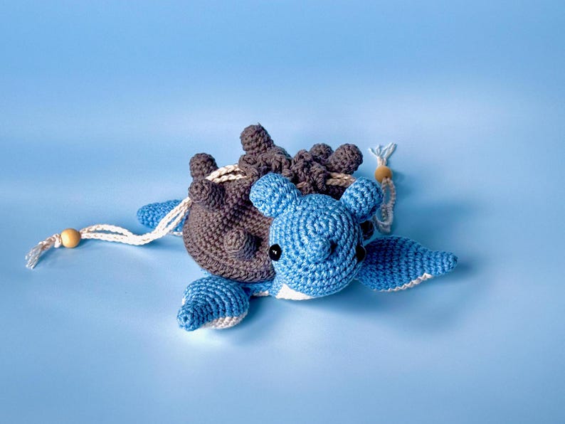 May include: A crocheted blue and brown turtle toy with a white string attached. The turtle has a brown shell with a blue head and legs.