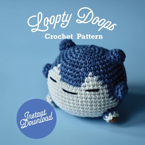 Puede incluir: Un juguete amigurumi de crochet azul y blanco que se asemeja a un personaje de dibujos animados. El juguete tiene un cuerpo redondo, orejas pequeñas y una cara sonriente. El texto "Loopy Doops Crochet Pattern" está por encima del juguete. El texto "Instant Download" está en un círculo debajo del juguete.