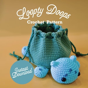 Può includere: Una borsa a cordoncino in crochet di colore turchese e blu a forma di tartaruga con il testo "Loopy Doops Crochet Pattern" e "Instant Download" su uno sfondo beige.