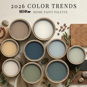 Puede incluir: Una colección de nueve latas de pintura abiertas con la paleta 2026 BEHR Color Trends. Los colores incluyen tonos beige, blanco, azul marino, azul claro, verde salvia y verde azulado oscuro, junto con muestras de madera y piedras.