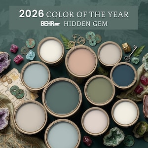 May include: A collection of round paint containers in various shades of blue, green, and neutral tones, arranged with decorative items including crystals, antique coins, and keys. The text 2026 COLOR OF THE YEAR BEHR HIDDEN GEM is displayed at the top.