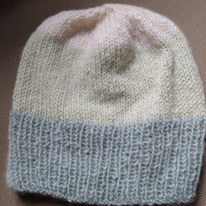 May include: A knitted hat with a light pink, light green, and gray color scheme. The hat has a ribbed brim.