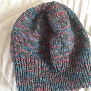 May include: A knitted beanie hat with a striped pattern in shades of blue, green, and red.