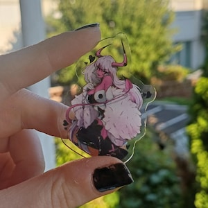 Könnte beinhalten: Ein klarer Acryl-Anhänger mit einem pinkhäutigen Anime-Charakter mit weißen Haaren, roten Hörnern und schwarzer Kleidung. Der Charakter trägt ein weißes, flauschiges Outfit. Der Anhänger hat ein herzförmiges Design.
