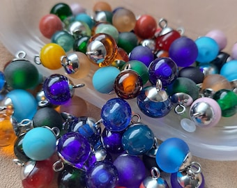 May include: Assortment of colorful glass beads with silver metal caps and loops. The beads are various shades of blue, green, purple, red, and brown.