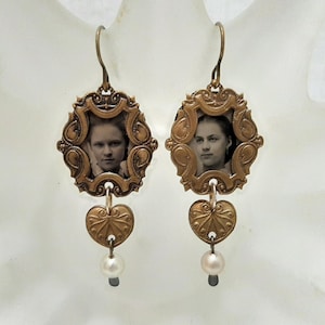May include: A pair of gold-toned earrings with a heart charm and a pearl dangle. Each earring features a framed photo of a young woman with a vintage look.