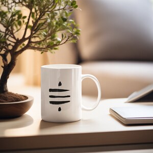 Puede incluir: Taza de cerámica blanca con un diseño abstracto negro. La taza tiene un asa y está sobre una mesa de madera.