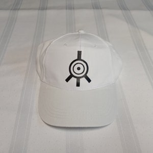 Peut inclure: Casquette de baseball blanche avec un symbole noir sur le devant. Le symbole est un cercle avec un cercle plus petit à l'intérieur, et trois lignes s'étendant du cercle.