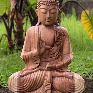 May include: A hand-carved wooden statue of Buddha sitting in a meditative pose. The statue is made of dark brown wood and has intricate details.