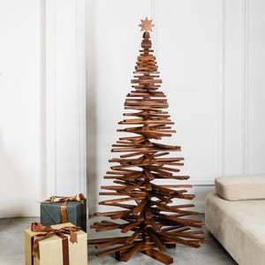 May include: A tall, conical Christmas tree sculpture constructed from stacked, horizontal dark brown wooden slats. The structure features a central vertical support and is topped with a small, eight-pointed wooden star ornament.
