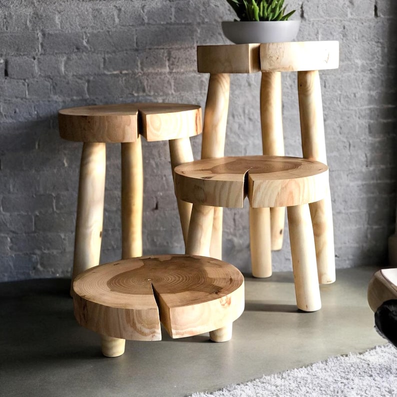 Op de afbeelding: Vier houten krukken in verschillende maten, elk met een ronde bovenkant en vier poten. De krukken zijn gemaakt van natuurlijk hout en hebben een rustieke, handgemaakte uitstraling.