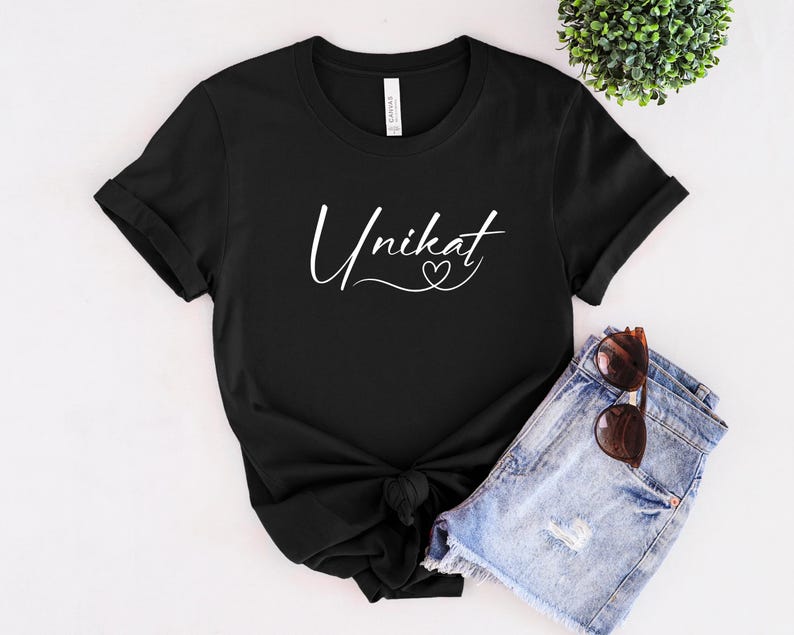 May include: Black t-shirt with white text that says "Unikat" with a small heart symbol.