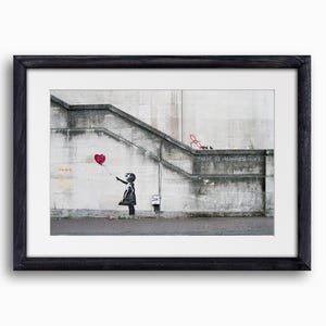 Könnte beinhalten: Eine schwarz-weiße Schablone eines Mädchens, das einen roten herzförmigen Ballon an einer grauen Betonwand loslässt, auf der die Worte "There is always hope" stehen.