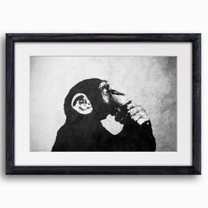May include: Black and white framed print featuring a chimpanzee in a thoughtful pose. The artwork has a minimalist style, with the chimpanzee's silhouette against a textured background. The frame is dark, enhancing the contrast.