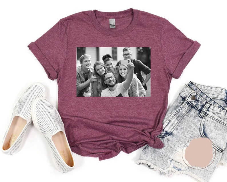 May include: A maroon t-shirt with a black and white photo of a group of friends taking a selfie. The photo shows six people smiling and looking at the camera.