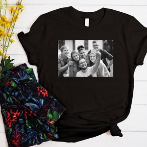 May include: Black and white photo of a group of friends taking a selfie. The photo is printed on a black t-shirt.