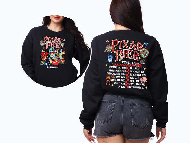 May include: Black sweatshirt with a graphic of Pixar characters on the front and a list of Pixar movies and release dates on the back. The text reads "Pixar Pier" and "Disneyland".