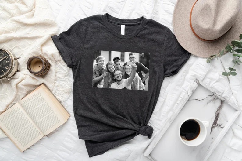 May include: A dark gray t-shirt with a black and white photo of a group of friends taking a selfie. The photo shows six people smiling and looking at the camera.