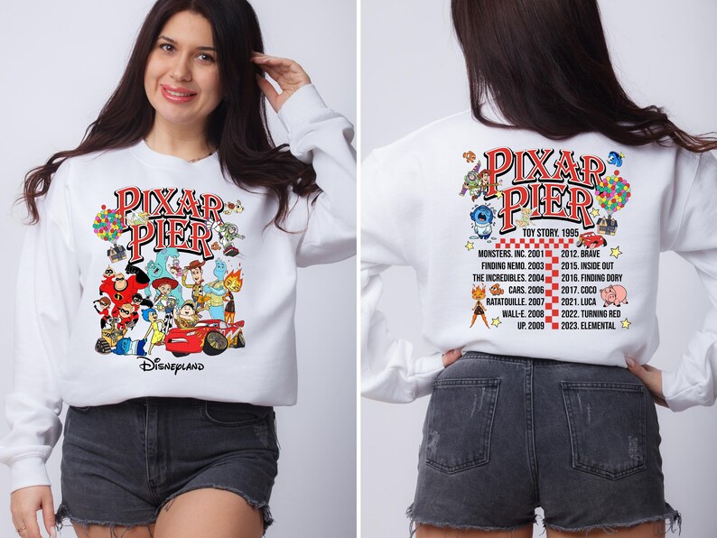 May include: White sweatshirt with a colorful graphic of Pixar characters and the text "Pixar Pier Disneyland". The back of the sweatshirt has a list of Pixar movies and their release years.