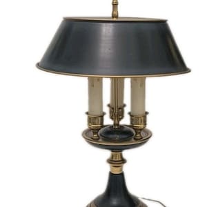 Pode incluir: Um candeeiro de mesa com um abajur cónico cinzento-escuro e uma pega em forma de anel de latão no topo. A base é composta por componentes pretos e de latão, suportando três casquilhos verticais tipo vela dispostos em círculo.
