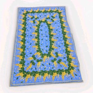 Könnte beinhalten: Eine rechteckige blaue Steppdecke mit floralem Design. Die Steppdecke hat ein zentrales blaues Feld mit verstreuten weißen Punkten. Ein Rand aus grünen Blättern und gelben Blüten umrahmt die Kanten. Die Steppdecke ist wahrscheinlich aus Baumwolle oder einem ähnlichen Stoff.